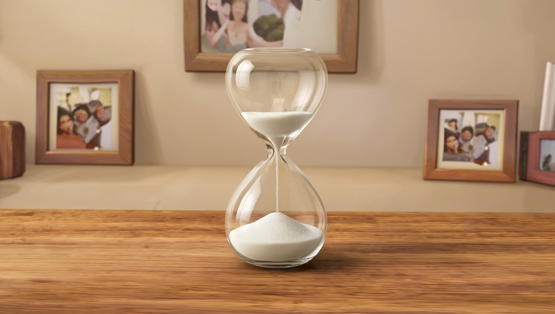 An hourglass with sand flowing, sitting on a wooden table.